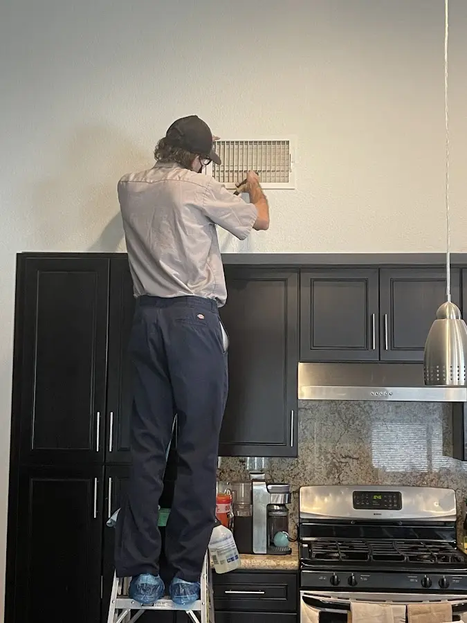 Technician inspecting an air vent during HVAC service in Lenoir City
